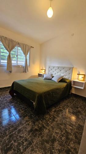 a bedroom with a large bed and two windows at El Cañaveral in Capilla del Monte
