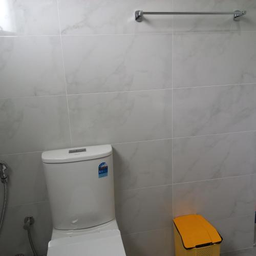 a white bathroom with a toilet and a yellow stool at Mirissa Cocoon in Mirissa