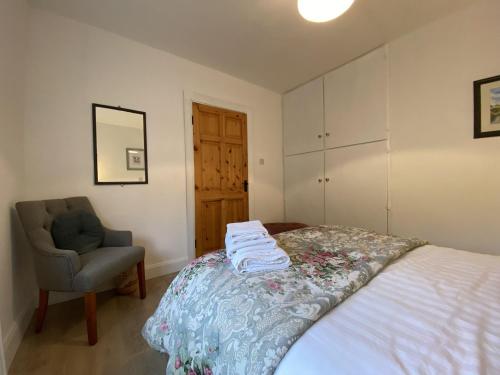 a bedroom with a bed and a chair and towels at Cottage 483 - Renvyle in Letterfrack