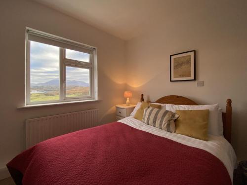 a bedroom with a bed with a red blanket and a window at Cottage 483 - Renvyle in Letterfrack