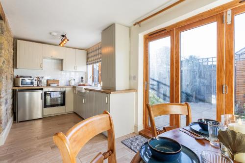 a kitchen and dining room with a table and chairs at Puddler's Cottage in Bedlington