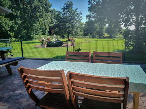 a table with three wooden chairs and a table with a glass table top at Auszeithof Otersen - Ferienwohnung 4 in Kirchlinteln