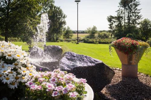 a fountain in a garden with flowers in a park at Auszeithof Otersen - Ferienwohnung 4 in Kirchlinteln