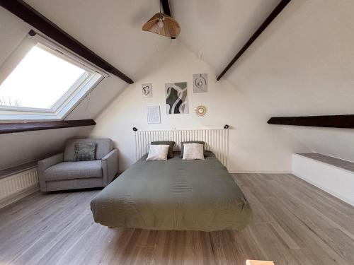 une chambre avec un lit et une chaise dans un grenier dans l'établissement La p'tite maison de cerisel avec piscine privée, à Les Chéris