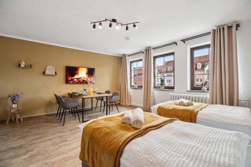 a hotel room with two beds and a dining area at CozyHome Hauptmarkt Apartments in Gotha