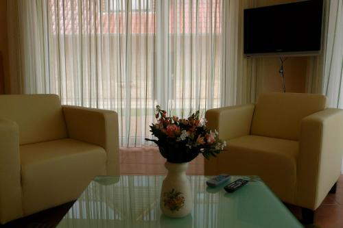 a living room with two chairs and a vase with flowers on a table at Ferienhaus direkt an See & Strand in Göhren-Lebbin