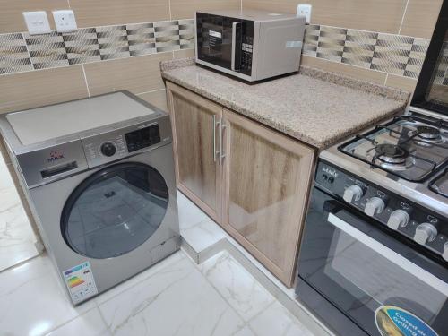 a kitchen with a microwave and a washing machine at Al Wesam Furnished Apartments in Aqaba