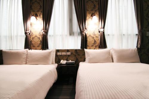 two beds in a hotel room with windows at LIHO Hotel Hankou in Taipei