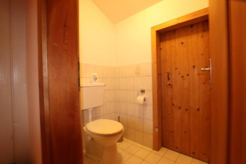 a bathroom with a toilet and a wooden door at Ferienwohnung Prent Wildschönau WILD023 by FeWo-Plan in Dorf