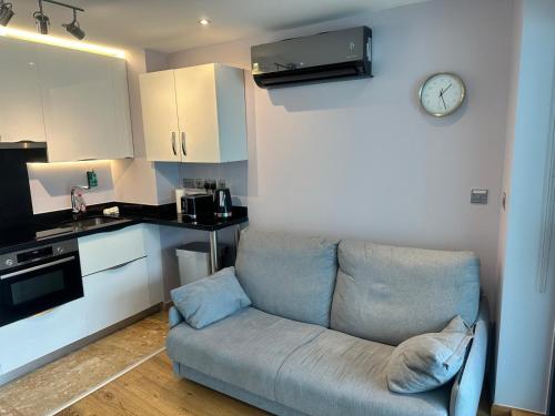 a living room with a couch and a clock on the wall at Seaside Serenity Oasis - High floor - Stunning Views in Gibraltar