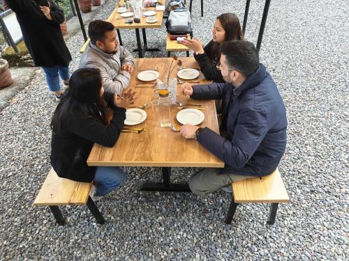 a group of people sitting at a wooden table at Treetop Glamps in Mussoorie