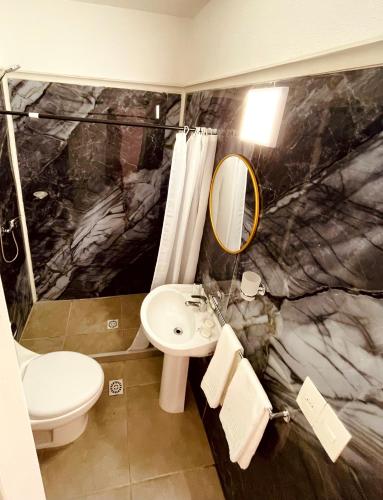 a bathroom with a sink and a toilet and a mirror at Hotel RICHMOND Punta del Este in Punta del Este