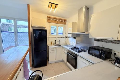 Il comprend une cuisine équipée de comptoirs blancs et d'un réfrigérateur noir. dans l'établissement Bulle Azur charming 3-room apartment, au Cannet