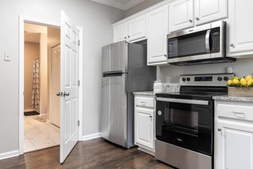 a kitchen with white cabinets and a black appliance at Stylish and Cozy Retreat in Buford