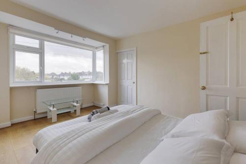 スタンウェルにあるModern 4 bedroom house in Heathrow, Londonの白いベッドルーム(ベッド2台、窓付)