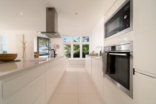 een witte keuken met witte kasten en een magnetron bij Ocean Terrace, Luxury Family Apt, Sea view and Terrace, 2 BR, Parking in Lynmouth