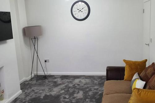 a living room with a couch and a clock on the wall at Exquisite and Modern 2 bed Maisonette in Harmondsworth