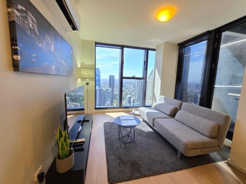 a living room with a couch and large windows at Melbourne CBD Southern Cross Collins St Skyline View Balcony in Melbourne