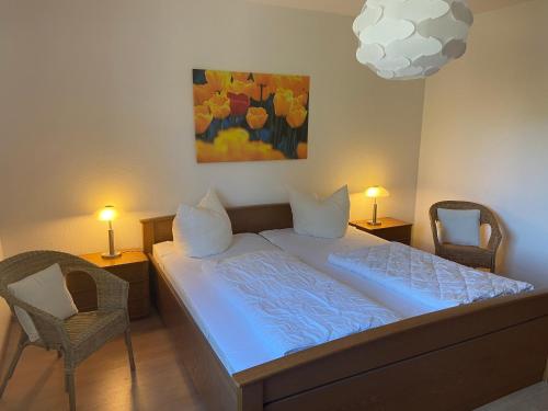 ein Schlafzimmer mit einem Bett mit 2 Stühlen und einem Gemälde in der Unterkunft Meeresrauschen - a57320 in Zingst
