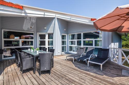 une terrasse avec une table, des chaises et un parasol dans l'établissement Hus Lykke - Strandpark 38, à Grömitz