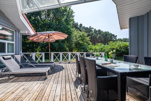 un patio avec une table, des chaises et un parasol dans l'établissement Hus Lykke - Strandpark 38, à Grömitz