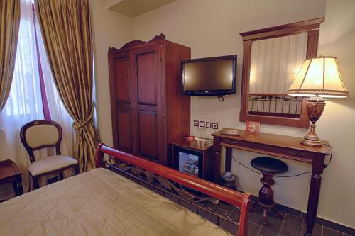 a bedroom with a bed and a television and a desk at Theofilos Paradise Boutique Hotel in Mytilini