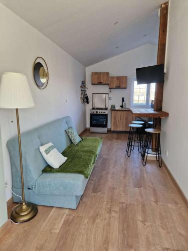 a living room with a blue couch and a kitchen at Maisonnette indépendante in Lœuilley