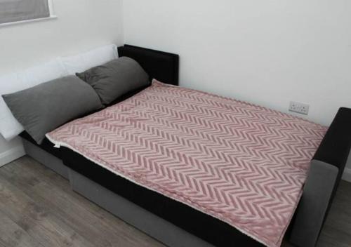 a bed with a pink blanket on top of it at Newly Refurbished 3 Bed 2.5 Bath House in Staines in Staines