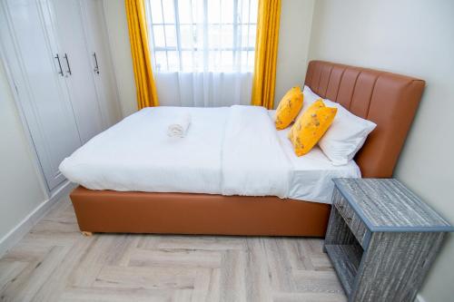 a small bedroom with a bed with yellow pillows at Blink comfort suite- Rhino in Ngong