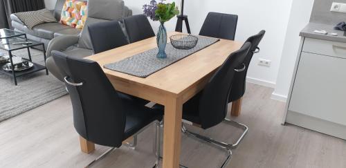 ein Holztisch mit schwarzen Stühlen und einer Vase mit Blumen in der Unterkunft FeWo Prora - Ausblick in Binz