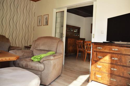 Una sala de estar con una silla y un televisor. en Superior - Ferienhaus am Engelsbach mit Garten und Pool, en Engelsbach