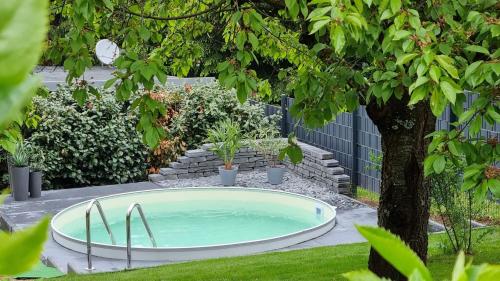 a hot tub in a garden with a tree at Superior - Ferienhaus am Engelsbach mit Garten und Pool in Engelsbach