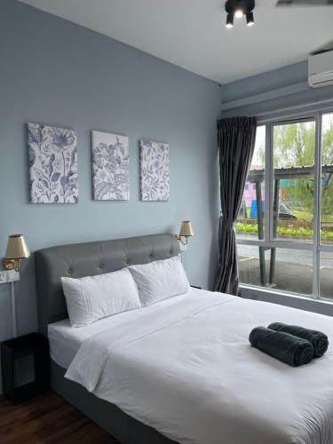 a bedroom with a bed with white sheets and a window at Bunga Home with swimming pool access in Lahad Datu