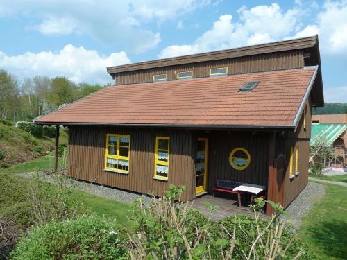 a small house with yellow windows and a roof at Ferienhaus Nr 11B2, Feriendorf Hagbügerl, Bayr Wald in Waldmünchen