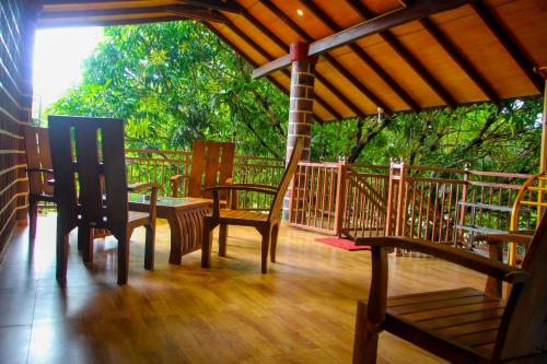 a porch with chairs and a table on a wooden floor at Sigiriya Peacock Homestay in Sigiriya