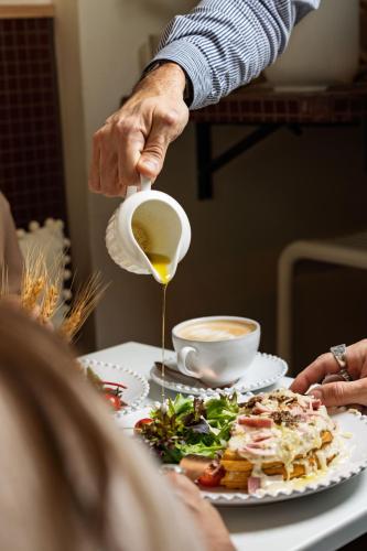 a person pouring honey onto a plate of food at Hotel M Soleil - Montpellier Centre Saint Roch in Montpellier