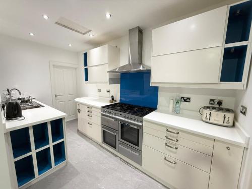 a kitchen with white cabinets and a stove top oven at Cozy 3 bedroom home in Wyken - Coventry in Wyken