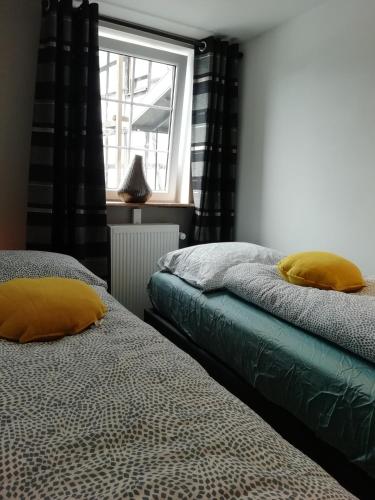 two beds with yellow pillows in a room with a window at Haus Blick am Edersee 13 p in Waldeck