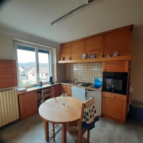 une cuisine avec une table en bois et une table et des chaises dans l'établissement Le Camp Du Tustal, à Saint-Julien-de-Lampon
