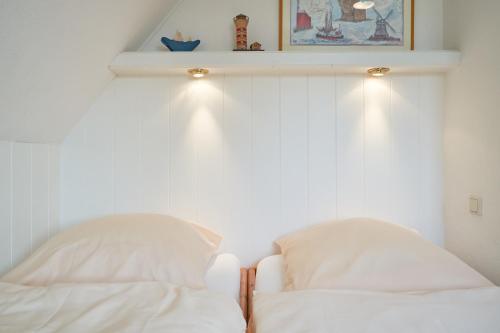 a bedroom with white walls and two pillows at Apfelgarten in Boldixum
