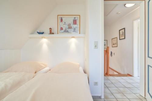 a white bedroom with a bed and a staircase at Apfelgarten in Boldixum