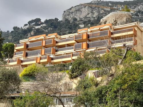 un bâtiment sur le côté d'une colline plantée d'arbres dans l'établissement appartement côte d'azur vue mer, à Roquebrune-Cap-Martin
