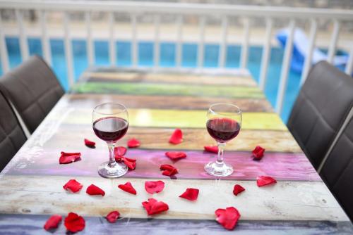 two glasses of red wine on a table with roses at Villa Maya The Royal Links Sarigerme in Sarigerme
