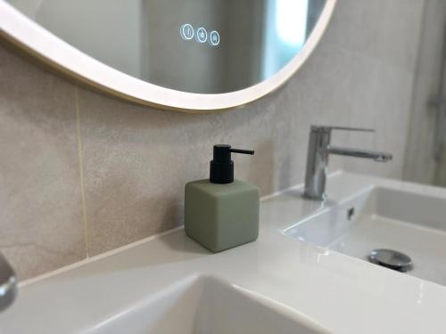 un dispenser di sapone su un lavandino del bagno di fronte a uno specchio di Maison centre ville La Tranche sur mer a La Tranche-sur-Mer