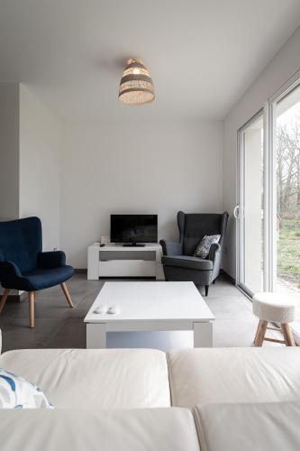 un salon avec un canapé blanc et des chaises dans l'établissement La Maison aux Chevreuils, à Parentis-en-Born