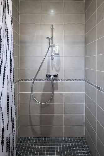 La salle de bains carrelée est pourvue d'une douche avec un tuyau. dans l'établissement La Maison aux Chevreuils, à Parentis-en-Born