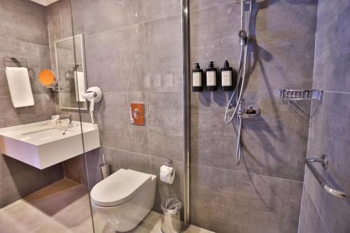 a bathroom with a shower and a toilet and a sink at Caddem Inn Hotel in Mağusa