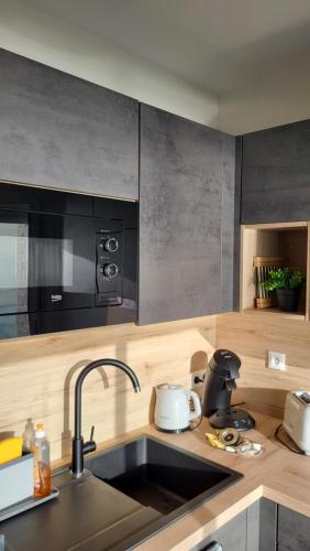 une cuisine avec un évier et un micro-ondes dans l'établissement Appartement de charme, face à l'ocean, à Saint-Jean-de-Monts