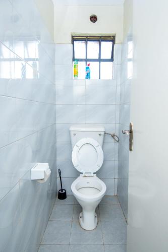 a white toilet in a bathroom with a window at Blink comfort suite- Lion in Ngong
