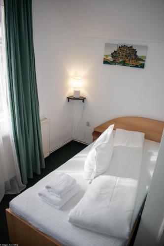a bedroom with a bed with white sheets and pillows at Pensiune Restaurant Căprioara Toplița in Topliţa